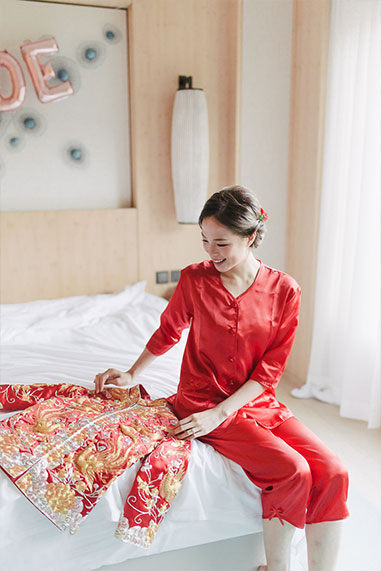 bride smiles on bed with chinese wedding attire