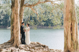 bride and groom pose next to lake
